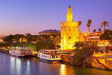 Tour boats moored on the Guadalquivir river near the Torre del Oro at sunset, Seville, Andalusia, Spain, Europe