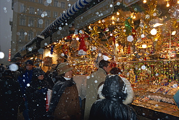 People shopping as snow falls at a Christmas market stall, Marienplatz, Munich, Bavaria, Germany, Europe