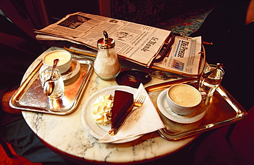 Coffee desserts and a newspaper on a table in the Sacher Cafe