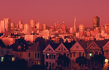 The famous Victorian Painted Ladies of Steiner Street, Alamo Square, with city skyline at dusk, San Francisco, California, USA