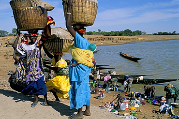 Women with baskets of laundry on their heads beside the river, Djenne, Mali, Africa