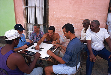 A group of men sitting around a table playing dominoes outdoors, Trinidad, Cuba, West Indies, Central America