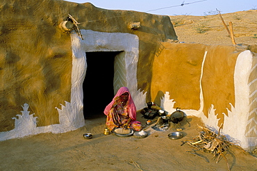 Woman cooking outside house with painted walls, village near Jaisalmer, Rajasthan state, India, Asia