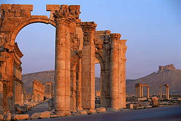 Monumental arch at archaeological site, with Arab castle beyond, Palmyra, UNESCO World Heritage Site, Syria, Middle East