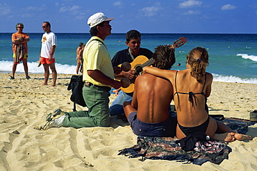 Couple sitting on the beach listening to two musicians, La Habana, Cuba, West Indies, Central America