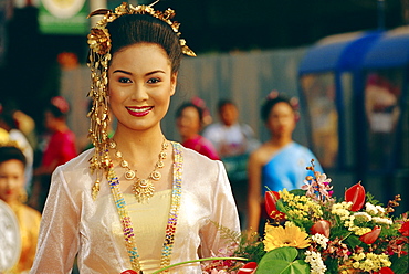Portrait of a young Thai 'queen' holding flowers competing for 'Flower Festival Queen' title, Chiang Mai, Thailand