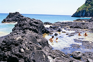 People swimming at Baia dos Porcos inside natural swimming pools, Parque Nacional de Fernando de Norohna, Fernando de Noronha, Pernambuco, Brazil, South America