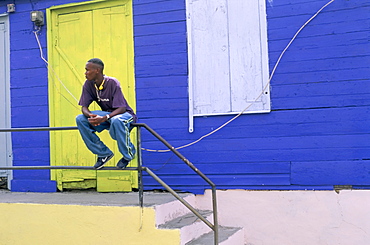 Young man sitting outside house, Antigua, Leeward Islands, West Indies, Caribbean, Central America