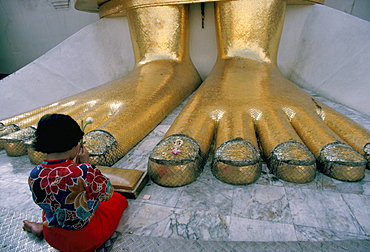 Woman praying at the feet of the Buddha in the temple of the Standing Buddha, Wat Intrawiharn, Bangkok, Thailand, Southeast Asia, Asia