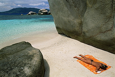 Woman sunbathing on beach beween rocks, Coco Island, Praslin, Seychelles, Indian Ocean, Africa