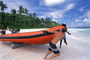 Launching inflatable boat on beach, nature reserve, Ile Aride (Aride Island), Seychelles, Indian Ocean, Africa