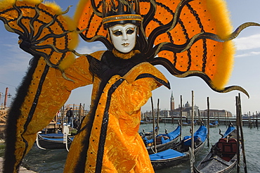 Masked faces and costumes at the Venice Carnival, with gondolas on waterfront and San Giorgio Maggiore behind, Venice, Veneto, Italy, Europe