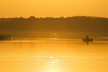 Sunset on lake and fishing boat, Aukstaitija National Park, Lithuania's first national park, Lithuania, Baltic States, Europe