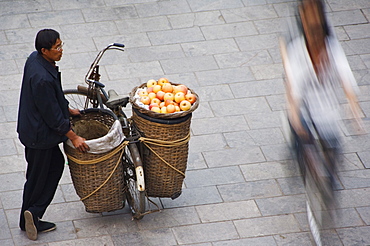 A fruit seller watching people pass by in the historic old town of Pingyao City, Shanxi Province, China, Asia