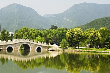 An arched stone bridge reflecting in a lake at Beijing Botanical Gardens, Beijing, China, Asia