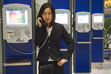 A Chinese business woman making a telephone call at Beijing Capital Airport part of new Terminal 3 building opened February 2008, second largest building in the world, Beijing China, Asia