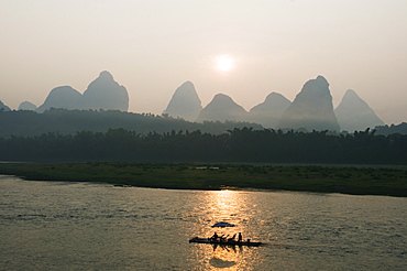 Tourist boat sailing through karst scenery at sunrise on the Li river (Lijiang) in Yangshuo, near Guilin, Guangxi Province, China, Asia