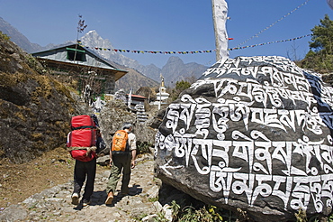 Trekkers walking past a mani stone, Solu Khumbu Everest Region, Sagarmatha National Park, Nepal, Asia