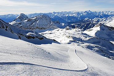 Skiers skiing on a ski run, mountain scenery in Cervinia ski resort, Cervinia, Valle d'Aosta, Italian Alps, Italy, Europe