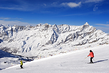 Skiers skiing on a ski run, mountain scenery in Cervinia ski resort, Cervinia, Valle d'Aosta, Italian Alps, Italy, Europe