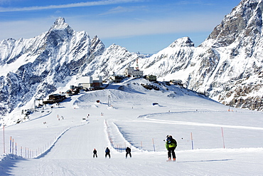 Skiers skiing on a ski run, mountain scenery in Cervinia ski resort, Cervinia, Valle d'Aosta, Italian Alps, Italy, Europe