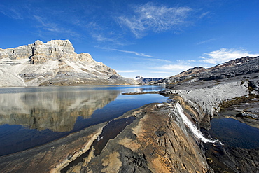 Waterfall and reflection of mountains in Laguna de la Plaza, El Cocuy National Park, Colombia, South America