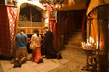 Priest and tourists praying in the Church of the Nativity (birth place of Jesus Christ), Bethlehem, Israel, Middle East