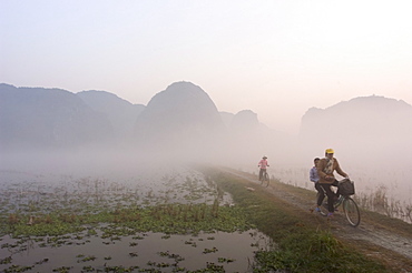 Bicycles in the morning mist at sunrise, limestone mountain scenery, Tam Coc, Ninh Binh, south of Hanoi, North Vietnam, Southeast Asia, Asia