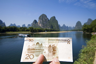 A tourist showing a RMB$20 note printed with the Guilin landscape as background, Xingping, Guilin, China