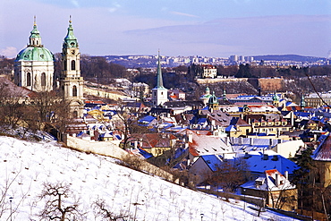 Snow covered Schonbornska Garden, Baroque St. Nicholas church and Mala Strana suburb rooftops in winter, Hradcany, Prague, Czech Republic, Europe