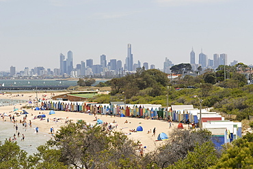 Beach scene with beach huts at Brighton Beach, Brighton, and in background skyscrapers of the city of Melbourne, Victoria, Australia, Pacific