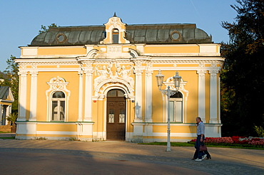 Spa building dating from the 19th century and promenading couple in the spa town of Frantiskovy Lazne, Karlovarsky Region, West Bohemia, Czech Republic, Europe