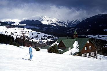 Winter view of skier on slopes at Pec Pod Snezkou with Snezka Mountain (1602m) in background, Krkonose Mountains, Bohemia, Czech Republic, Europe