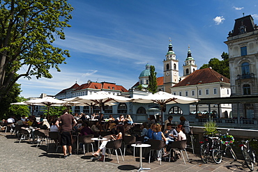 Outdoor cafes along the Ljubljanica river and the Cathedral of Saint Nicholas in the background, Ljubljana, Slovenia, Europe