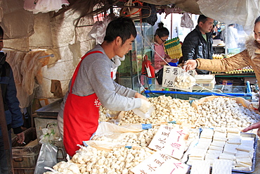 Man selling different varieties of tofu in a market in Kunming, China