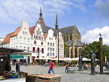 Traditional houses buildt in the middle ages at the  Neuer Markt (new market) and church Marienkirche in the background. The hanseatic city of Rostock at the coast of the german baltic sea.  Europe,Germany, Mecklenburg-Western Pomerania, June