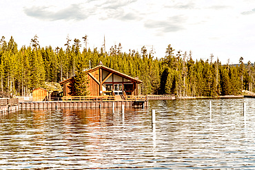 Wooden homr on Yellowstone Lake with trees water reflections.