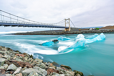 Jokulsarlon lake with icebergs at sunset, Iceland. Long exposure view with bridge on the background.