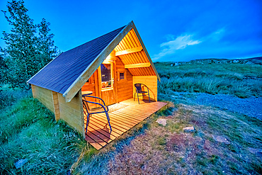 Beautiful chalet isolated in the mountains at sunset. Wooden front with chairs