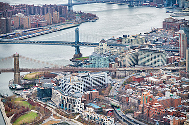 New York City from helicopter point of view. Brooklyn and Manhattan Bridges with Manhattan skyscrapers on a cloudy day.