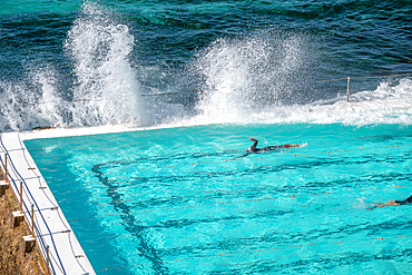 Swimmers enjoy beautiful pool along the sea.