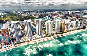 Aerial view of North Miami Beach skyscrapers with sun and clouds.