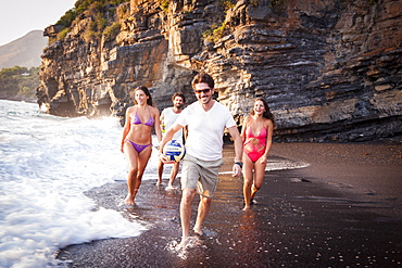 Group of smiling boys and girls on the Black Beach of Maratea at sunset, Basilicata, Italy, Europe