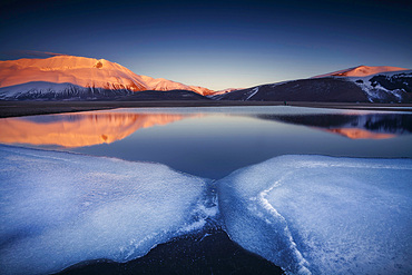 Beautiful landscape in Castelluccio di Norcia during a frozen sunset on Mount Redentore reflected in the lake, Umbria, Italy, Europe