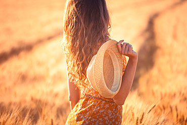 Beautiful girl in a wheat field. Natural sunlight during sunset, Italy, Europe