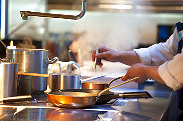 Hands of chefs at the stove; Italy