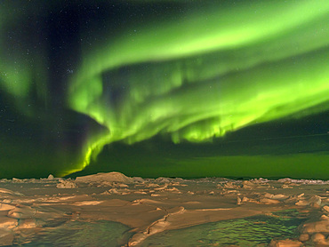 Northern lights over the shore of the frozen Disko Bay. Town Ilulissat at the shore of Disko Bay in West Greenland. The icefjord nearby is listed as UNESCO world heritage. America, North America, Greenland, Denmark