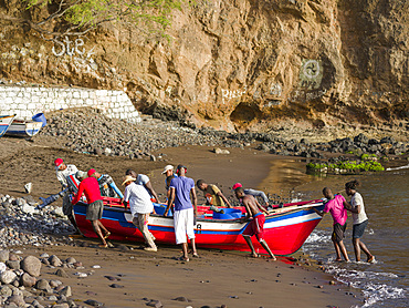 Fishermen and colorfull traditional fishing boats at the historic waterfront. Cidade Velha, historic center of Ribeira Grande, listed as UNESCO world heritage. Island of Santiago (Ilha de Santiago), Islands of Cape Verde in the equatorial Atlantic.