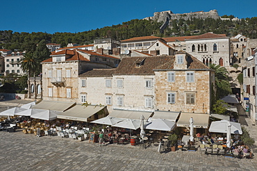 Pavement cafes in the main square overlooked by the ancient fortress, in the medieval city of Hvar, island of Hvar, Dalmatia, Croatia, Europe