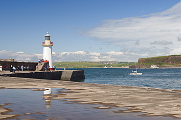 Lighthouse at entrance to outer harbour, motor yacht entering, Whitehaven, Cumbria, England, United Kingdom, Europe